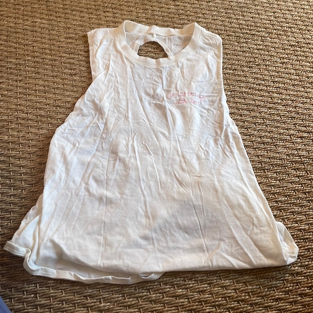 white athletic tank top. Says “do all things with love” sewn on the front